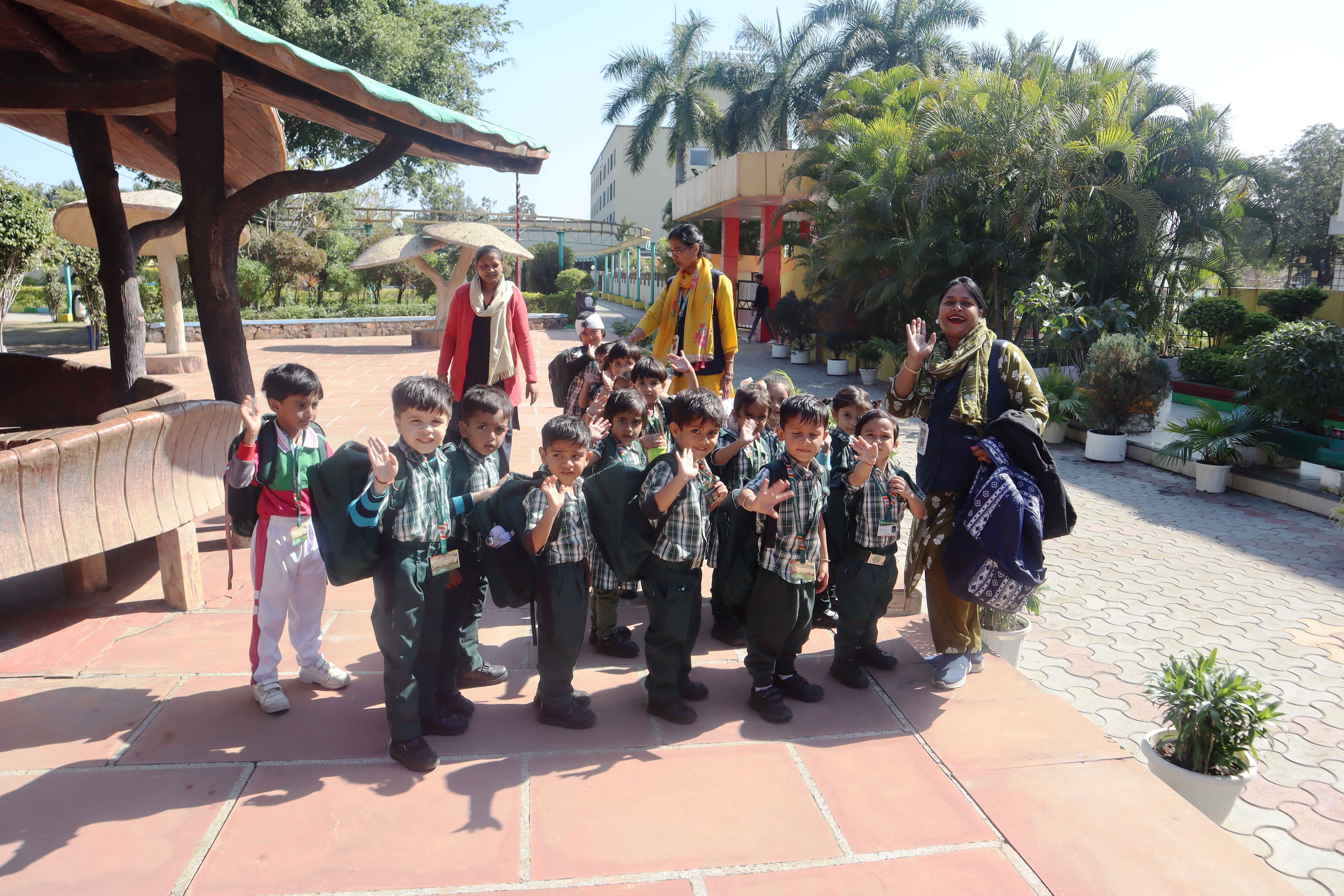 Children waving to the camera with their teachers during an outing